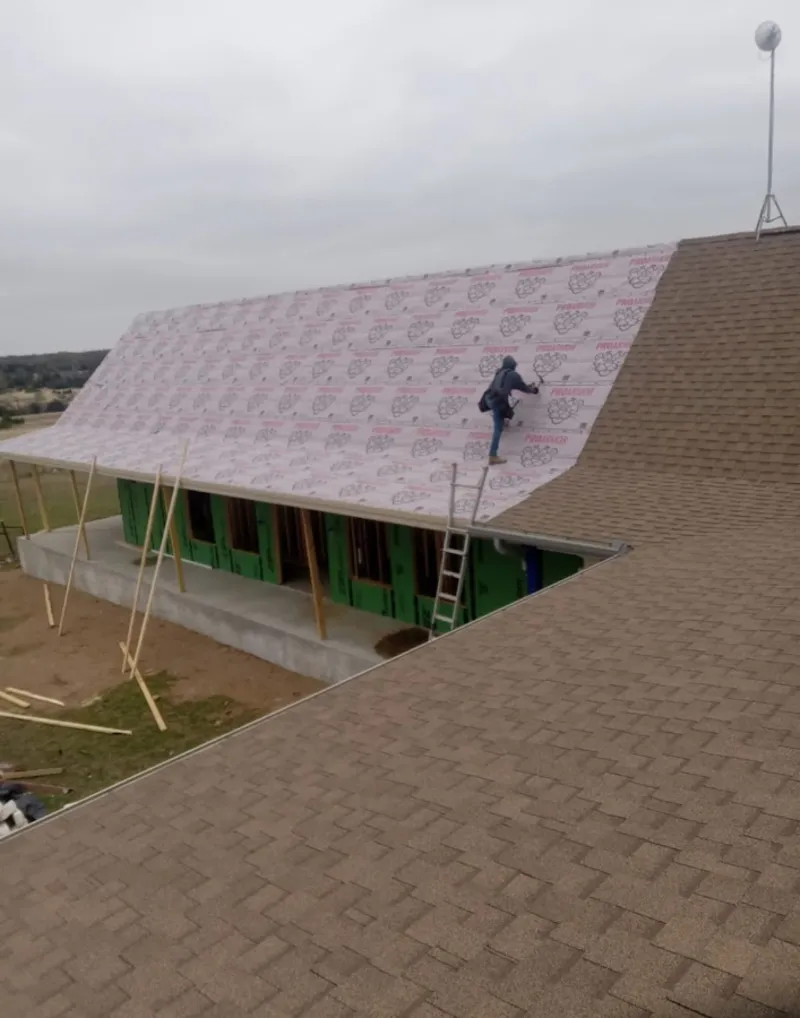 Worker preparing underlayment for a metal roof installation in Woodstock